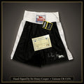 Sir Henry Cooper signed black Lonsdale London boxing shorts, size M, with swing tag and Liaisons UK Ltd COA, on a dark background with a gold border and caption